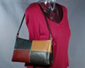 frame shoulder purse that narrows at top, curves slightly under arching single cord strap to give flowing contour; midway between the single strap north-south and east-west designs