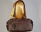 dark brown travelers shoulder bag with zippered side pockets and corner reinforcements
