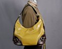 green hobo edged with coffee brown leather-like strap, edge and corner; harness boot rings and rivets accent lower corners