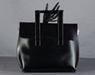 black handbag with flap closure, square handles, and smooth, polished leatherette